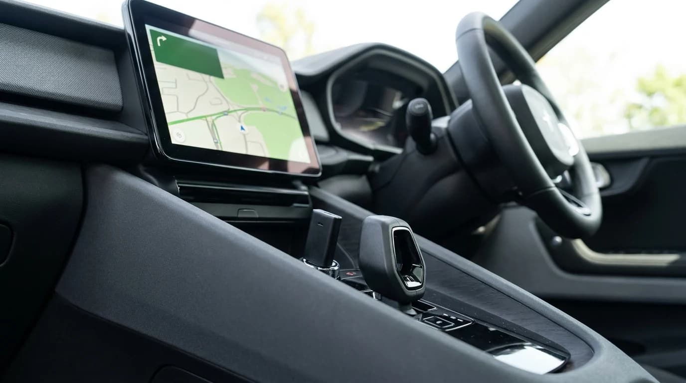 A small wireless adapter dongle plugged into a car's USB port with a phone-projection map screen lit on the dashboard display.